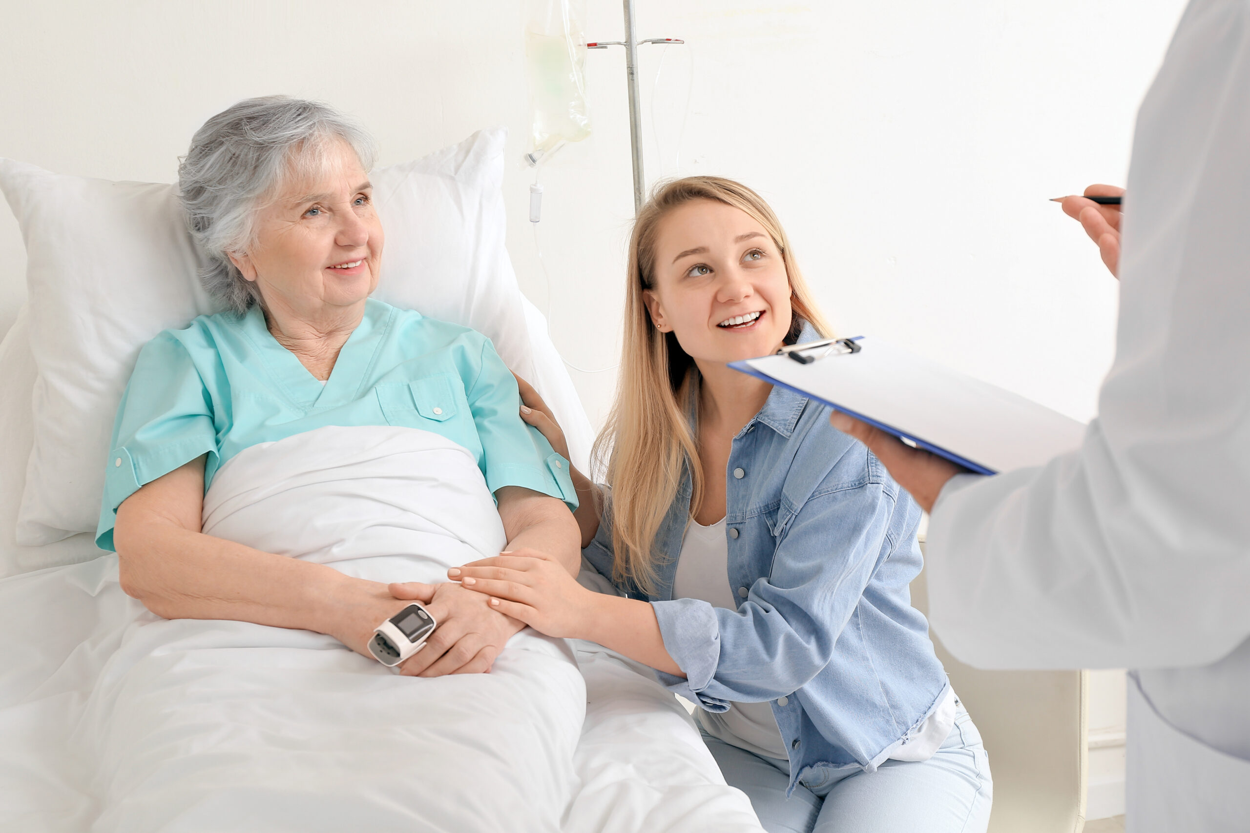 Young woman visiting her grandmother in hospital Elderly patient and family member talking to physician at the bedside